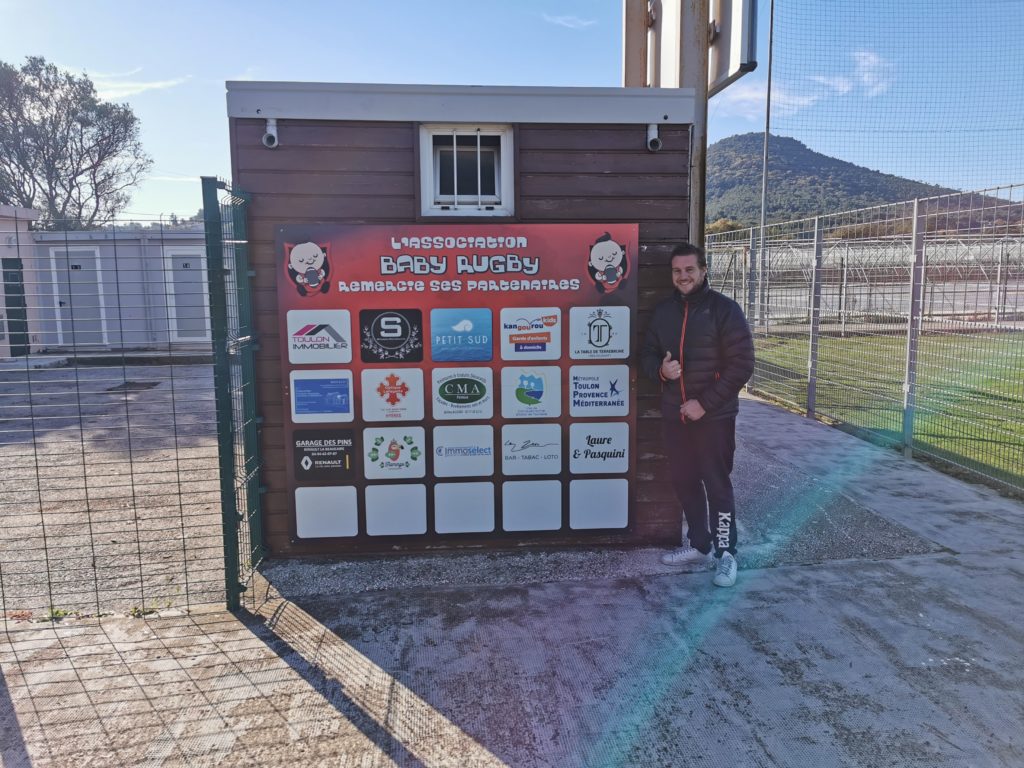 Bastien Miquelis lors de la mise en place du panneau des partenaires au stade Tassy de Carqueiranne.